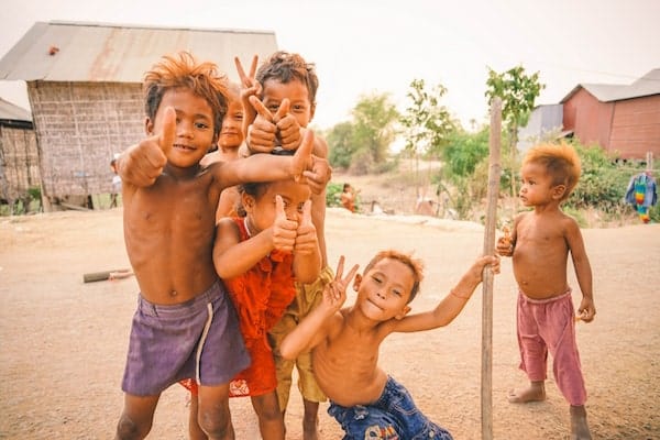 6 poor but happy children making peace signs