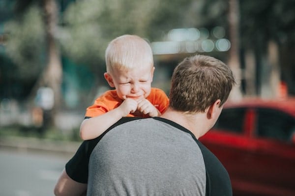 angry and aggressive toddler being carried gently by father