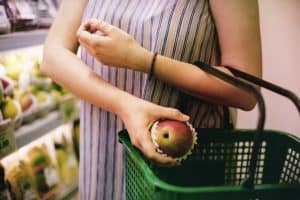 Woman grocery shopping and placing fruit in basket