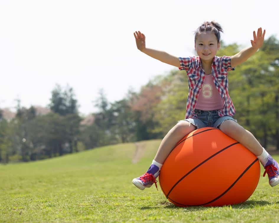 Girl balancing on giant basketball