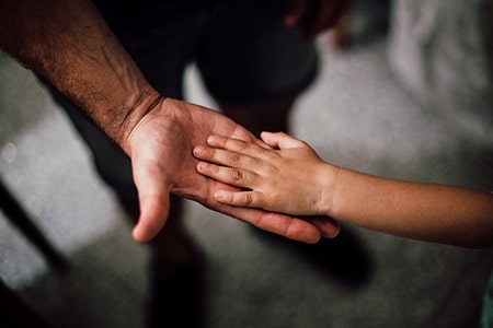 Child playing hand on a dad's hand